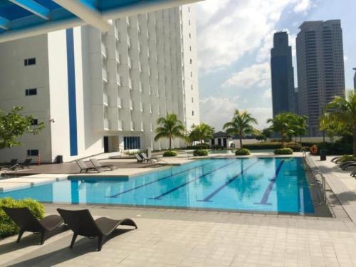 a large swimming pool with chairs and a building at Resort-Style Living at the 'Wall Street of the Philippines' in Makati! Enjoy the epitome of luxury near NAIA Airport & BGC, FREE POOL ACCESS, WIFI, and NETFLIX. Secure Your Limited Offer This Month! in Manila