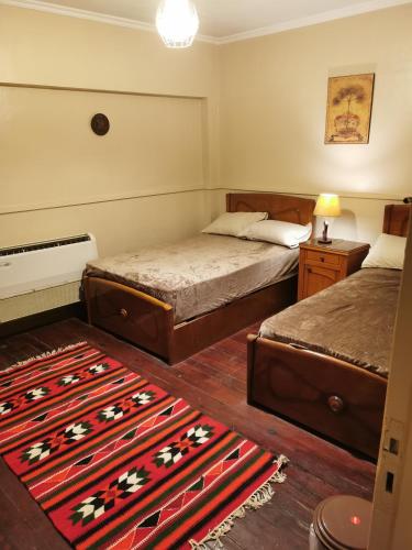 a bedroom with two beds and a rug at Adham's Inn in Cairo