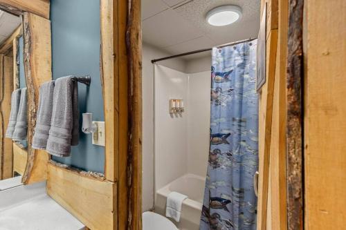 a bathroom with a shower with a blue shower curtain at Stonegate Lodge Pool Fire Pits King BedFast WiFi 50in TV Room #209 in Eureka Springs