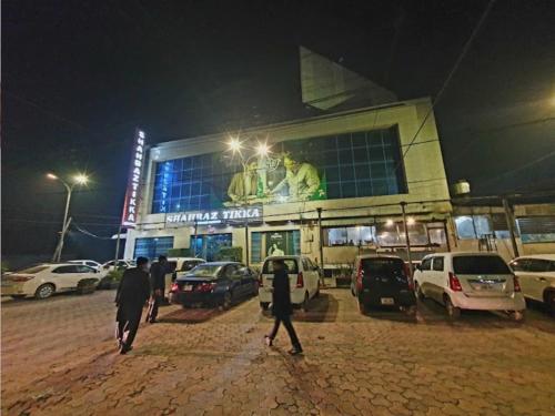 people walking in front of a building at night at Capital Lodges in Gujrānwāla