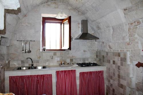 a kitchen with a sink and a stove and a window at Trulli Sulla Valle in Locorotondo