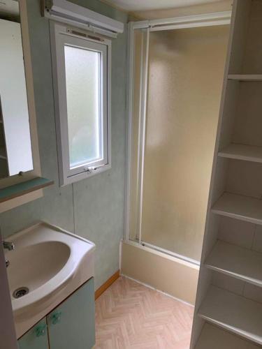 La salle de bains est pourvue d'un lavabo, d'une fenêtre et d'une douche. dans l'établissement Mobilhome, à Castillonnès