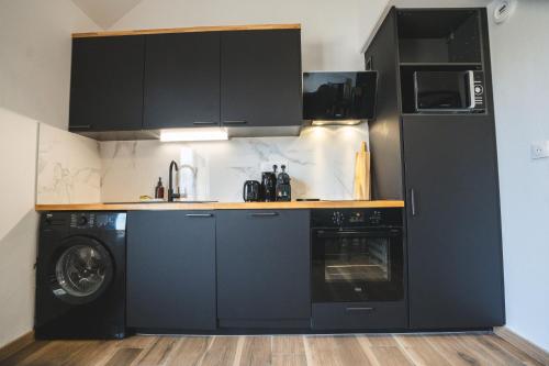 a kitchen with black cabinets and a washer and dryer at LE FACTORY aux pieds de la gare SNCF Laval in Laval