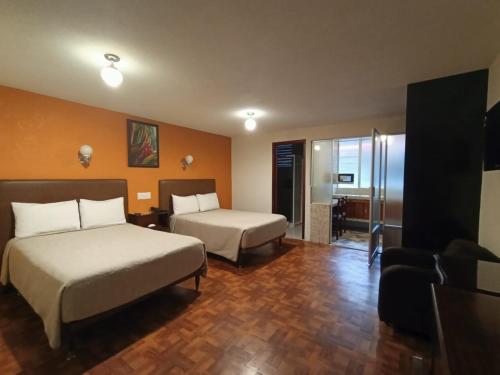 a hotel room with two beds and a living room at Hotel Suites Teziutlan in Teziutlán