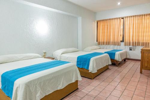 a hotel room with two beds and a window at Hotel El Mirador in Puerto Escondido