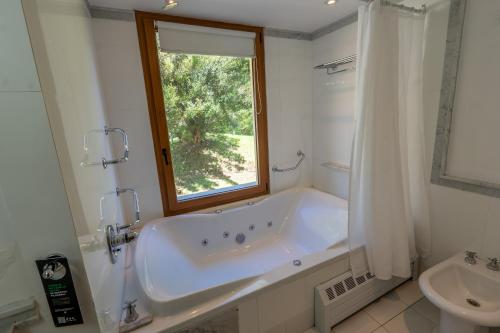 a white bathroom with a tub and a window at RentUp - Casa con vista panorámica al lago Nahuel Huapi in Villa La Angostura