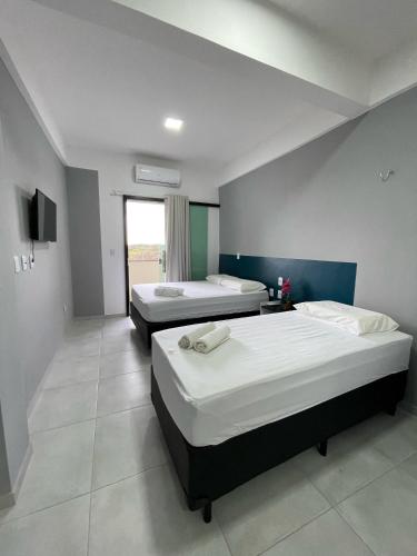 a bedroom with two beds and a television in it at HOTEL GATAO in Sobral