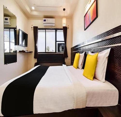 a bedroom with a large bed with yellow and white pillows at HOTEL SHIRDI IN in Shirdi