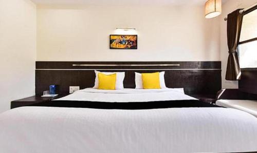 a bedroom with a large white bed with yellow pillows at HOTEL SHIRDI IN in Shirdi