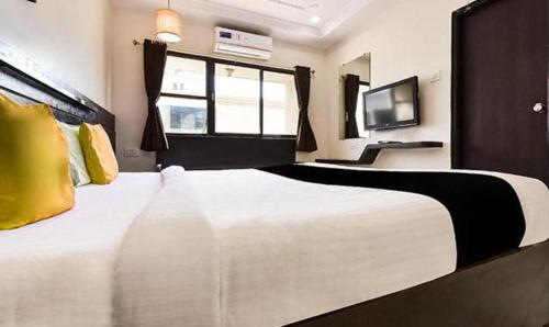 a bedroom with a large white bed and a tv at HOTEL SHIRDI IN in Shirdi