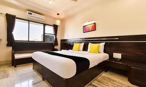 a bedroom with a large bed with yellow pillows at HOTEL SHIRDI IN in Shirdi