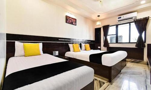 a bedroom with two beds with yellow and black pillows at HOTEL SHIRDI IN in Shirdi