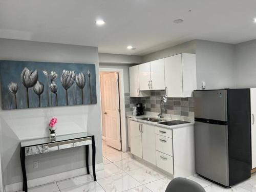 uma cozinha com armários brancos e um frigorífico preto em LIGHTHOUSE em Surrey