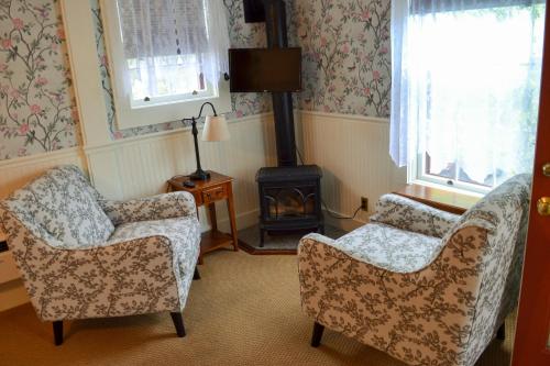 a living room with two chairs and a wood stove at Black Friar Inn and Pub in Bar Harbor