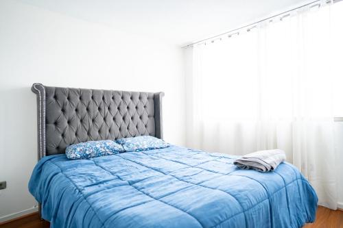 um quarto com uma cama com um edredão azul em Céntrico departamento a pasos del metro Rondizzoni. em Santiago