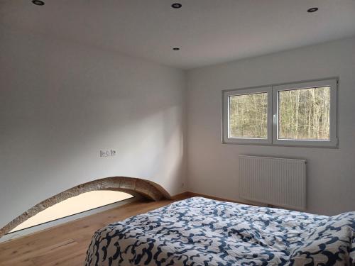 ein Schlafzimmer mit einem Bett und zwei Fenstern in der Unterkunft Les chambres du Haras St Georges in Athesans