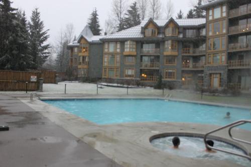 a swimming pool in front of a large building at Cascade Lodge suite GENIUS SPECIAL WIFI cable HDTV across from Whistler Village air conditioning heating pay underground parking pool 2 hot tubs sauna gym in Whistler