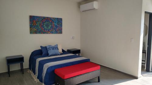Un dormitorio con una cama con un banco rojo y una pintura en Studios V19 en Colima