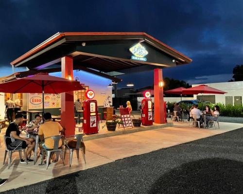 a gas station with people sitting at tables and umbrellas at The Perfect Studio in Arecibo