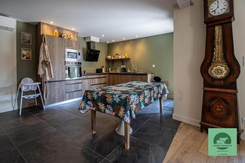 a kitchen with a table and a grandfather clock at L’étable d’Auguste in Arreau