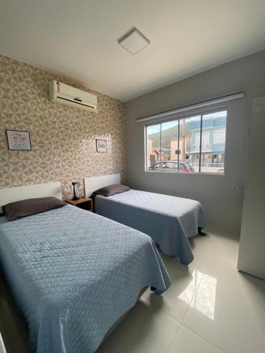 a bedroom with two beds and a window at Residencial Mariano 5 in Florianópolis