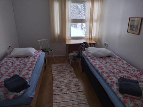 two beds in a small room with a window at Saarnimaja in Hämeenlinna
