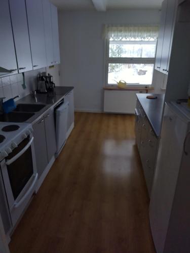 a kitchen with white appliances and a wooden floor at Saarnimaja in Hämeenlinna