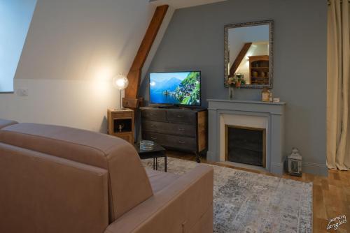 a living room with a television and a fireplace at Suite "États Généraux" face au château - LES SUITES DE BLOIS - 4 étoiles in Blois