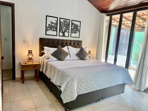 a bedroom with a large bed and a large window at Aconchego de geriba in Búzios
