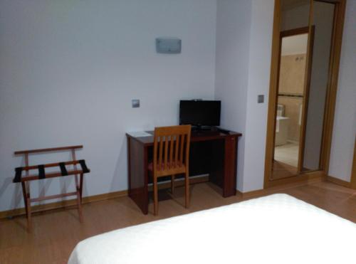 a bedroom with a desk and a chair and a television at Hotel San Cibrao in San Ciprián de Viñas