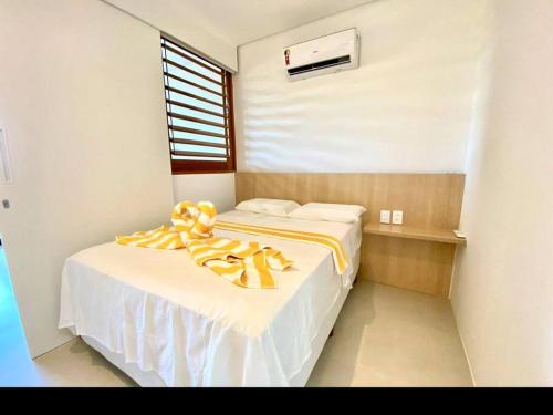 een slaapkamer met een bed met een gele deken erop bij Flat Eco Resort Praia Carneiros, Tamandaré. Porto dos corais 202 in Tamandaré
