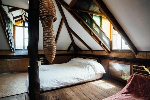 a bedroom with an attic with a bed and windows at Monsamkien Farmstay in Phayao