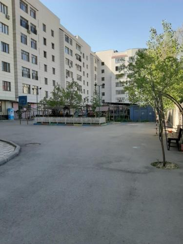 an empty parking lot with a tree and buildings at Apartment in the 7th Microdistrict in Bishkek