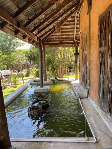 a pool of water with koi in a house at Monsamkien Farmstay in Phayao