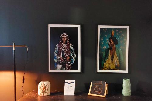 three framed pictures on a wall with a table at L'Aurore Berbère, hypercentre de Rouen, au calme in Rouen