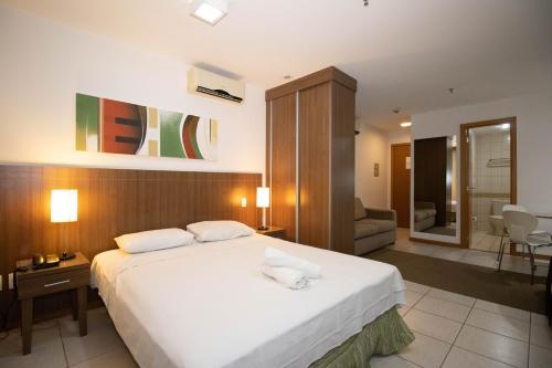 a bedroom with a large bed and a living room at Nobile, espaçoso e central. Com garagem! in Brasilia