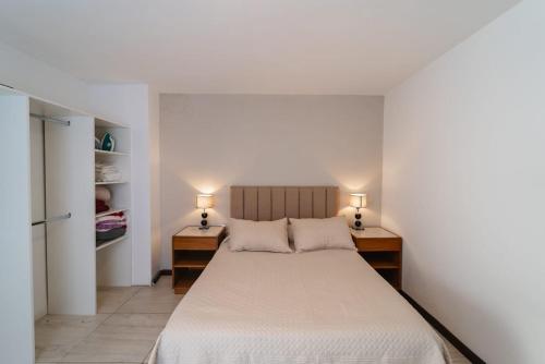 1 dormitorio con 1 cama y 2 mesitas de noche con lámparas en Complejo Lagrange en Córdoba