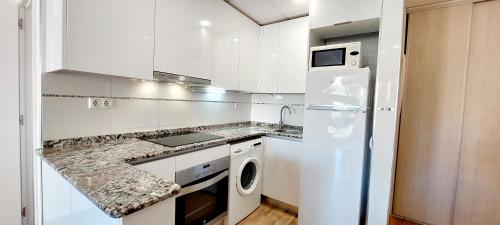 una cucina con armadietti bianchi e frigorifero bianco di Apartamento Lauren Salou a Salou