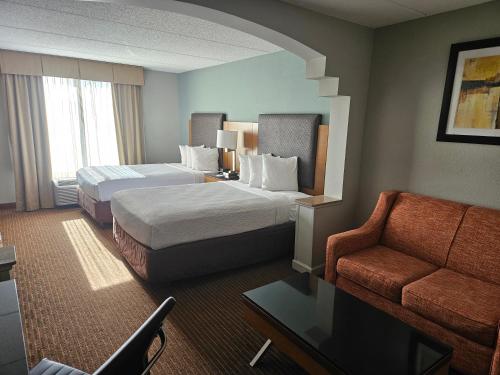 a hotel room with two beds and a couch at Wingate by Wyndham Greensboro-Coliseum in Greensboro