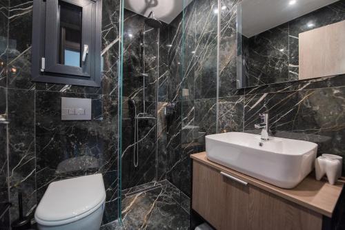 uma casa de banho com azulejos pretos, um WC e um lavatório. em Sansevieria Central em Tessalônica