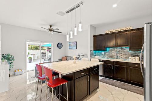a kitchen with a large island with red chairs at Lux Backyard/Heated Pool/Everglades/Speedway/Keys! in Miami
