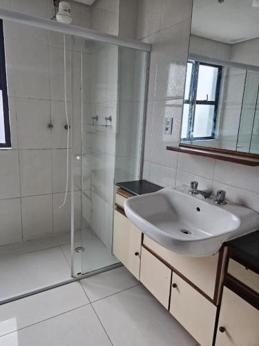 a white bathroom with a sink and a shower at Flat Palladium São Vicente in São Vicente