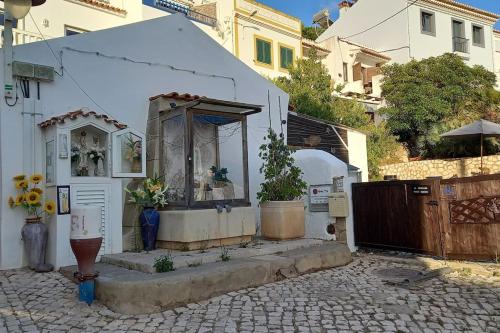 een klein wit huis met een poort en een binnenplaats bij Bica da Salema Beach House in Salema