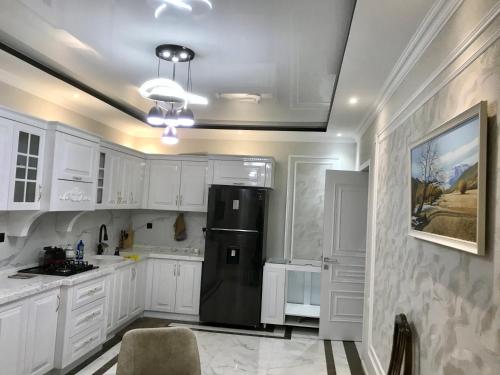 a kitchen with white cabinets and a black refrigerator at Вилла в г.Кусары in Qusar