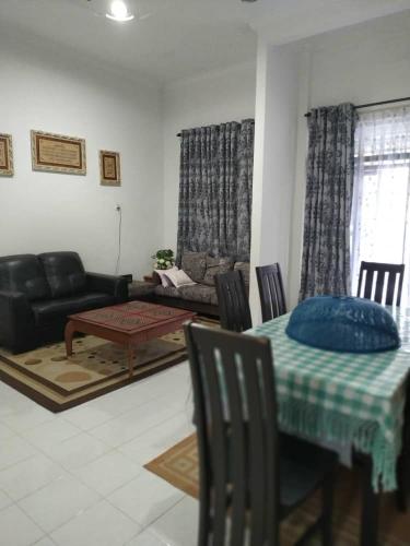 a living room with a table and a couch at Homestay Seri Aman Pasir Puteh 