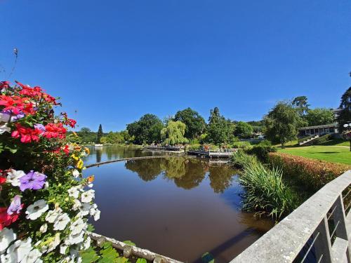 a view of a river with flowers on a bridge at La Potinière Du Lac Appartements in Bagnoles de l'Orne