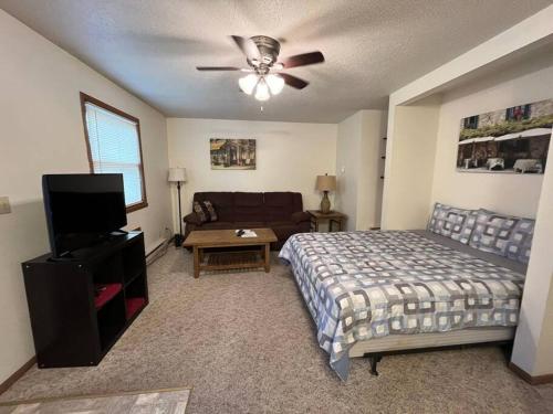 a bedroom with a bed and a couch and a ceiling fan at 201 E Veterans St Apt G by Patriot Properties in Tomah