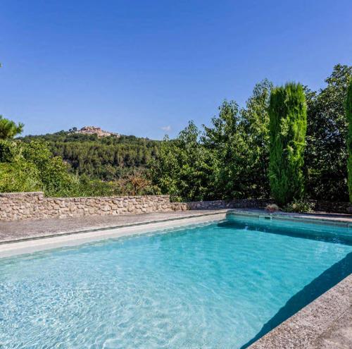 - une piscine avec un mur en pierre et des arbres dans l'établissement Auberge du Boisset, à Saint-Martin-de-Castillon