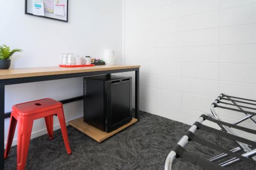 a desk with a black refrigerator and a red stool at Urban Lounge Sleepery in Rotorua
