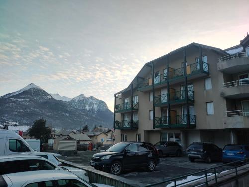 un estacionamiento con autos estacionados frente a un edificio en Chez Maxime Pre du Moulin en Briançon